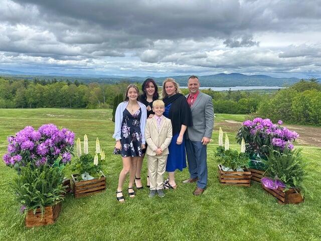 A mom and her three kids stand in front of a rack of girls clothes at their local BF sale.